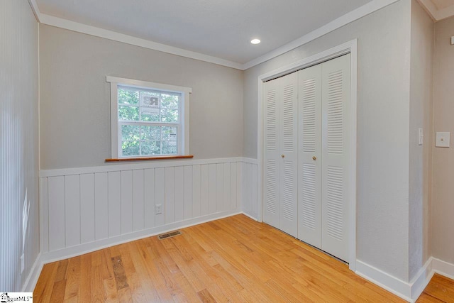 unfurnished bedroom with crown molding, light hardwood / wood-style flooring, and a closet