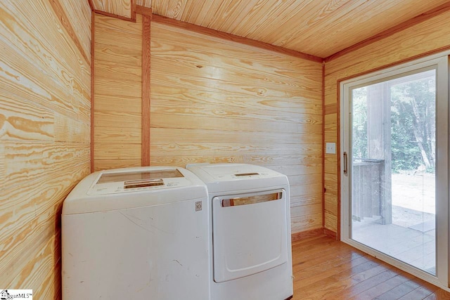 laundry area featuring washer and dryer, wooden walls, and light hardwood / wood-style floors