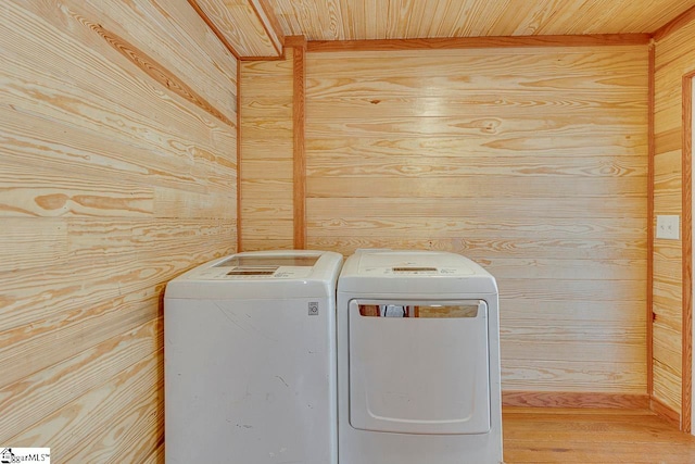 laundry room with wooden ceiling, independent washer and dryer, wooden walls, and hardwood / wood-style flooring