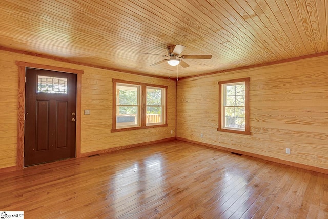 foyer entrance featuring wood ceiling, a healthy amount of sunlight, wood walls, and light hardwood / wood-style floors