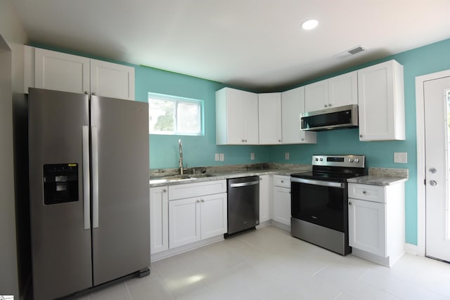 kitchen featuring sink, light tile patterned floors, appliances with stainless steel finishes, and white cabinets