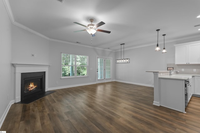 unfurnished living room with dark wood-style floors, a lit fireplace, ceiling fan, and crown molding