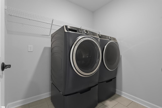 laundry room with washing machine and clothes dryer, laundry area, baseboards, and light tile patterned flooring