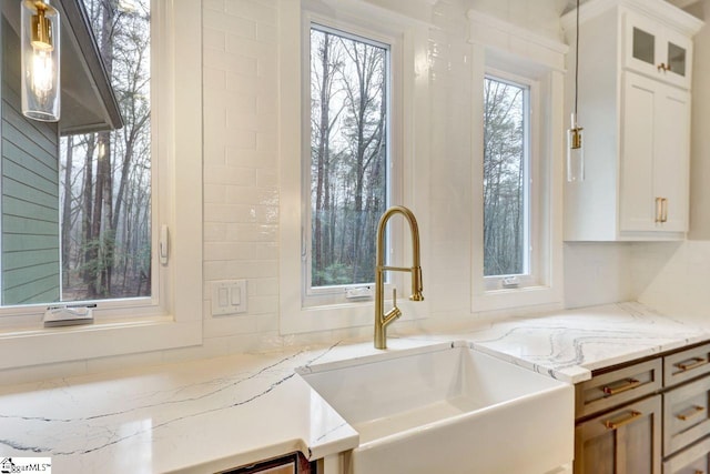 interior space featuring white cabinetry, sink, and light stone countertops