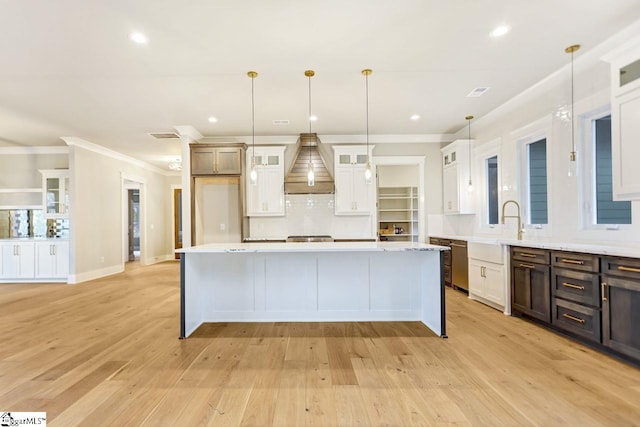 kitchen featuring backsplash, light hardwood / wood-style flooring, decorative light fixtures, white cabinetry, and premium range hood