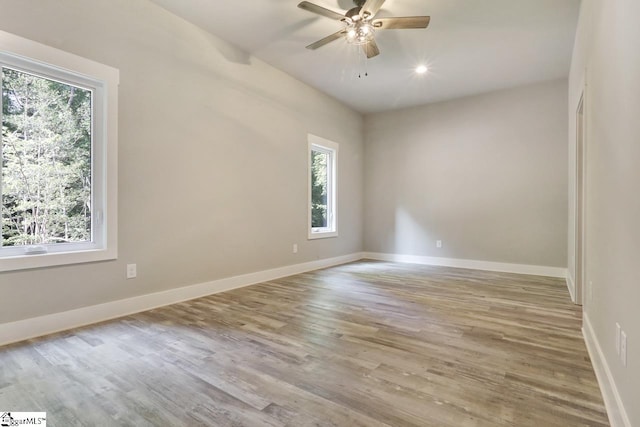 spare room with light hardwood / wood-style flooring, ceiling fan, and a healthy amount of sunlight