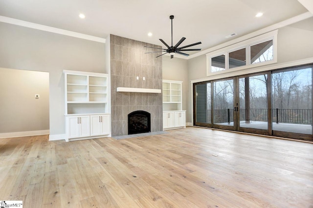 unfurnished living room featuring light wood-type flooring, a fireplace, a high ceiling, and ceiling fan