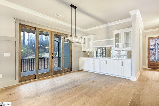 kitchen featuring light wood-type flooring, decorative light fixtures, tasteful backsplash, and a healthy amount of sunlight