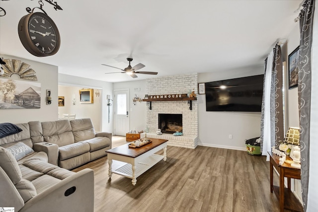 living room with brick wall, ceiling fan, wood-type flooring, and a fireplace