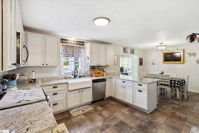 kitchen with dark tile patterned floors, light stone counters, stainless steel appliances, sink, and kitchen peninsula