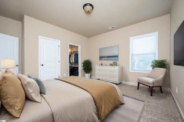 bedroom featuring a closet, carpet flooring, a walk in closet, and ensuite bathroom