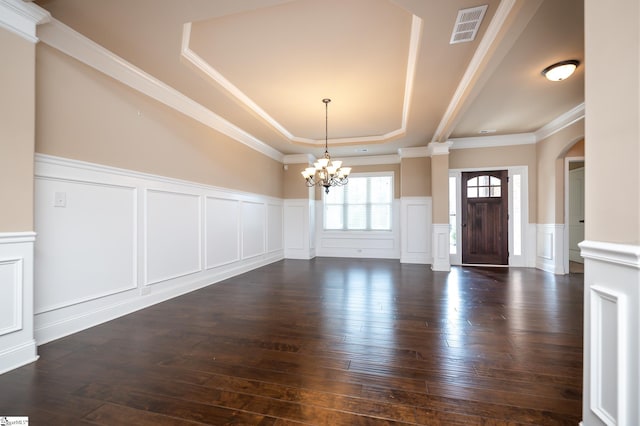 foyer with crown molding, dark hardwood / wood-style flooring, a chandelier, ornate columns, and a tray ceiling