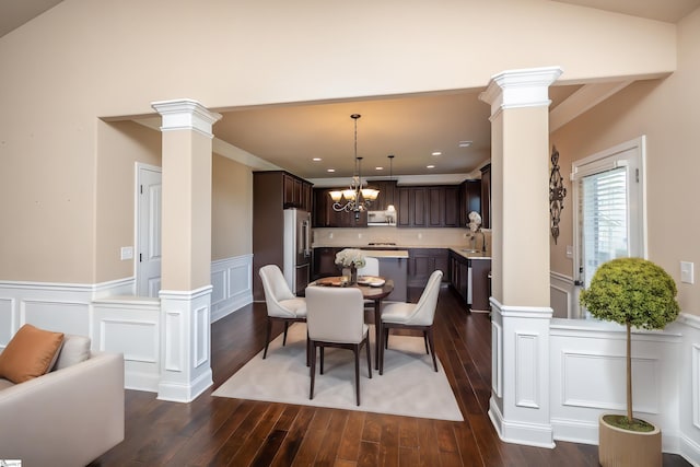 dining room with dark hardwood / wood-style flooring, a notable chandelier, and ornate columns