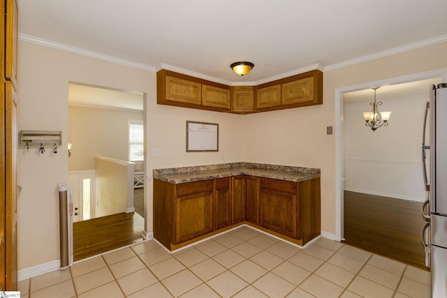 kitchen with crown molding, stainless steel fridge, light tile patterned floors, and a chandelier