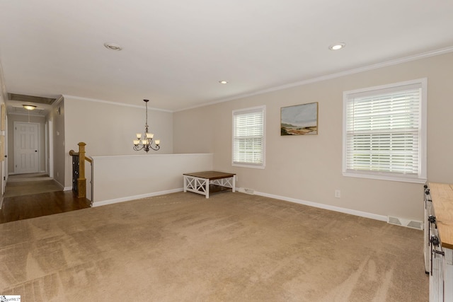 spare room with ornamental molding, a wealth of natural light, a chandelier, and carpet