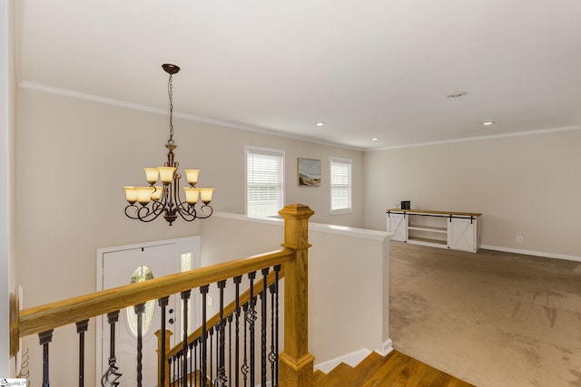 hall with crown molding, a notable chandelier, and carpet floors