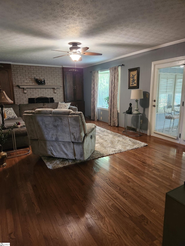 living room featuring ceiling fan, hardwood / wood-style flooring, a fireplace, and a textured ceiling