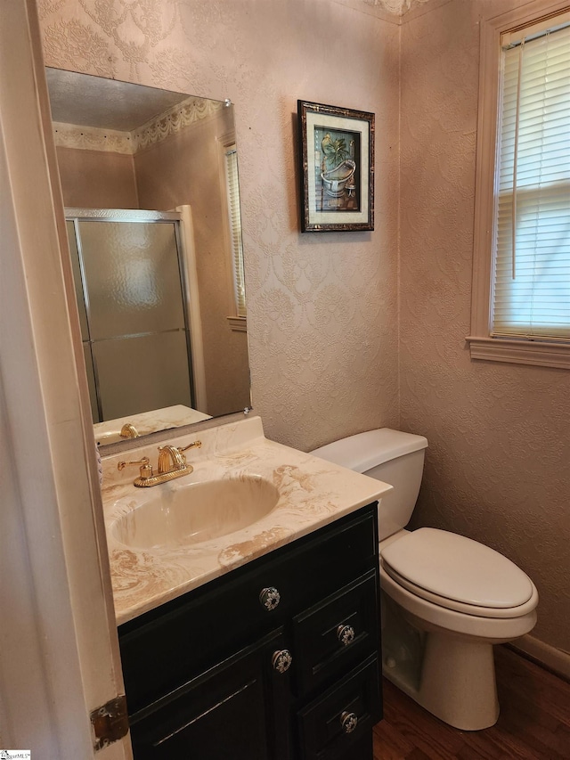 bathroom with vanity, toilet, hardwood / wood-style floors, and an enclosed shower