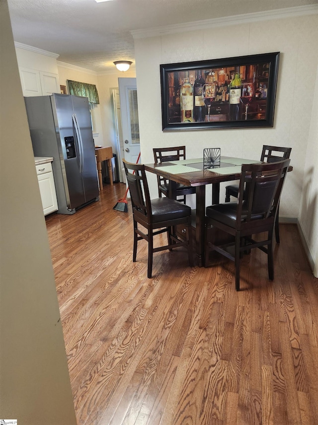 dining area with light hardwood / wood-style floors and ornamental molding