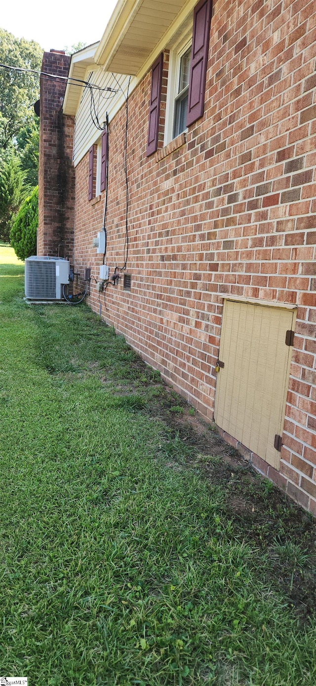 view of side of property with cooling unit and a lawn