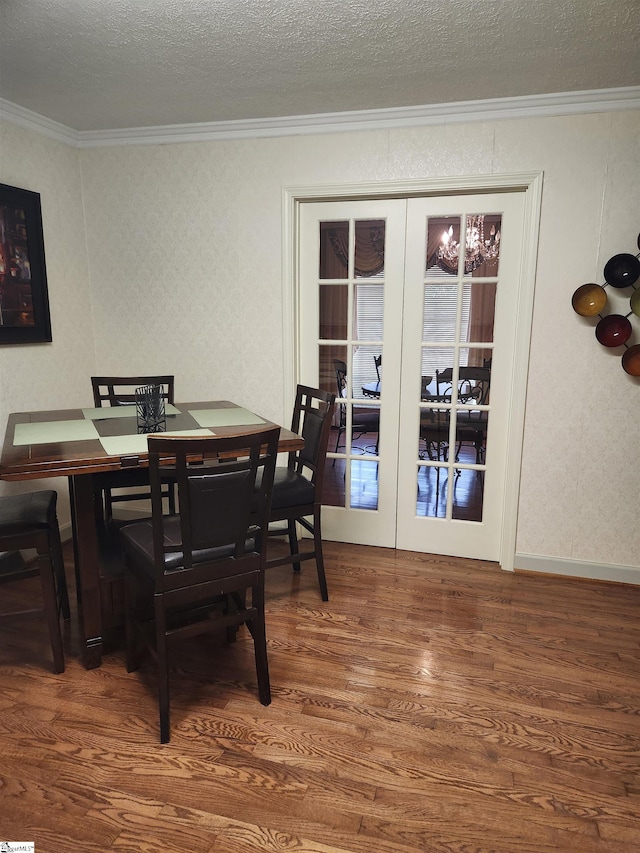 dining area with hardwood / wood-style flooring, ornamental molding, a textured ceiling, and french doors