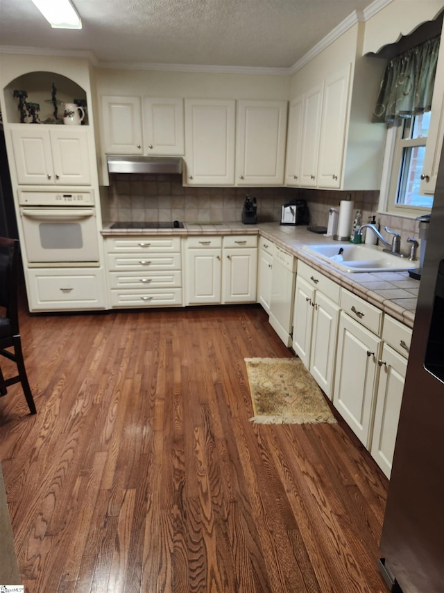 kitchen featuring dark wood-type flooring, white appliances, tile countertops, and sink