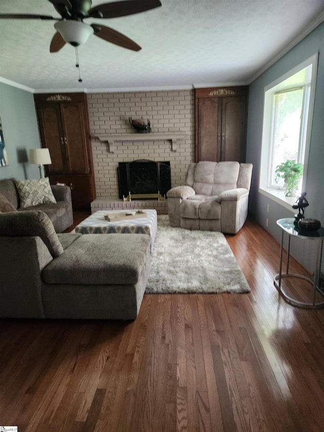 living room featuring hardwood / wood-style floors, crown molding, a brick fireplace, ceiling fan, and brick wall