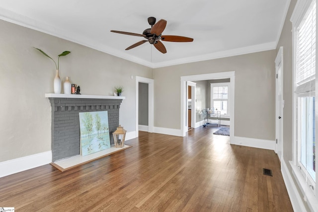 unfurnished living room with ornamental molding, ceiling fan, dark hardwood / wood-style floors, and a brick fireplace