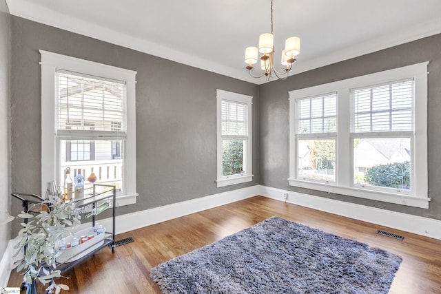 sitting room with ornamental molding, an inviting chandelier, and wood-type flooring