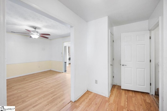 empty room with washer / dryer, a textured ceiling, ceiling fan, and light hardwood / wood-style floors