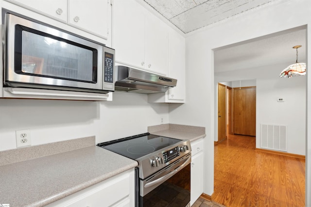 kitchen with appliances with stainless steel finishes, white cabinetry, and light hardwood / wood-style floors