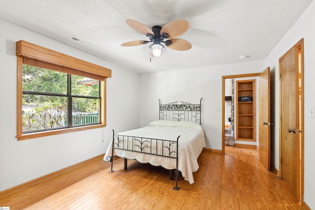 bedroom with a textured ceiling, light hardwood / wood-style flooring, and ceiling fan