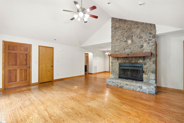 unfurnished living room with light hardwood / wood-style flooring, ceiling fan, high vaulted ceiling, and a stone fireplace