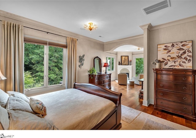 bedroom featuring ornamental molding, multiple windows, and hardwood / wood-style flooring