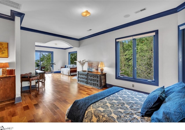 bedroom with multiple windows, wood-type flooring, and ornamental molding