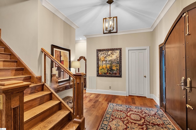 foyer entrance with crown molding, light hardwood / wood-style flooring, and a notable chandelier