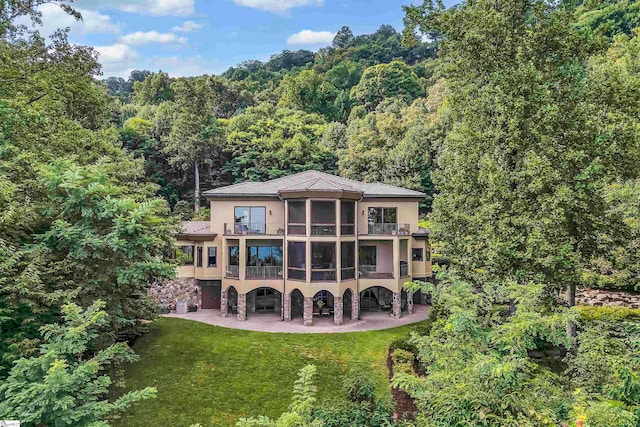 back of house with a balcony, a yard, and a patio