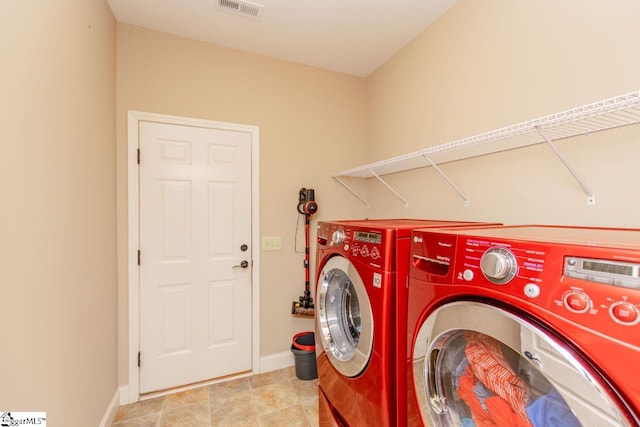 washroom featuring laundry area, washing machine and dryer, visible vents, and baseboards