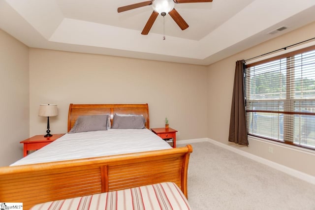 carpeted bedroom featuring a raised ceiling and ceiling fan