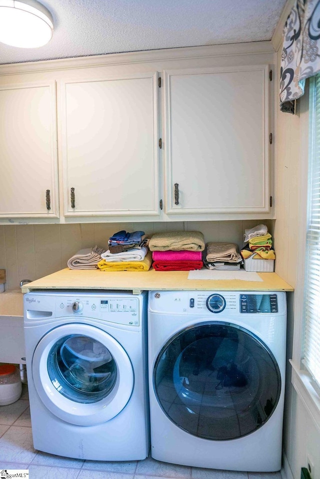 laundry area featuring light tile patterned floors, cabinets, and washer and clothes dryer