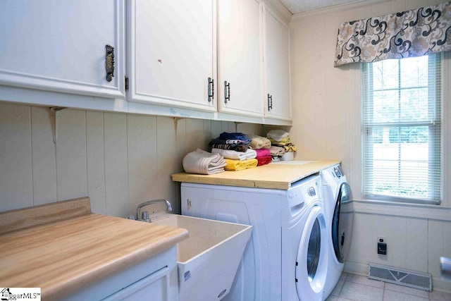 washroom featuring washer and dryer, cabinets, and light tile patterned flooring