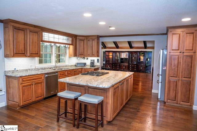 kitchen featuring stainless steel appliances, a center island, light stone countertops, sink, and dark hardwood / wood-style floors