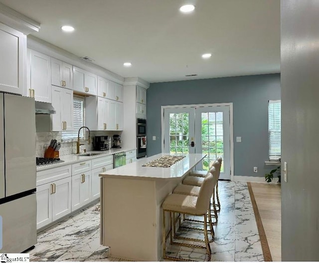 kitchen featuring appliances with stainless steel finishes, a kitchen island, sink, and white cabinets