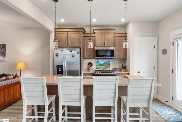 127 Addington Ln, Simpsonville, SC 29681 - kitchen with light wood finished floors, light stone counters, a kitchen breakfast bar, and stainless steel appliances