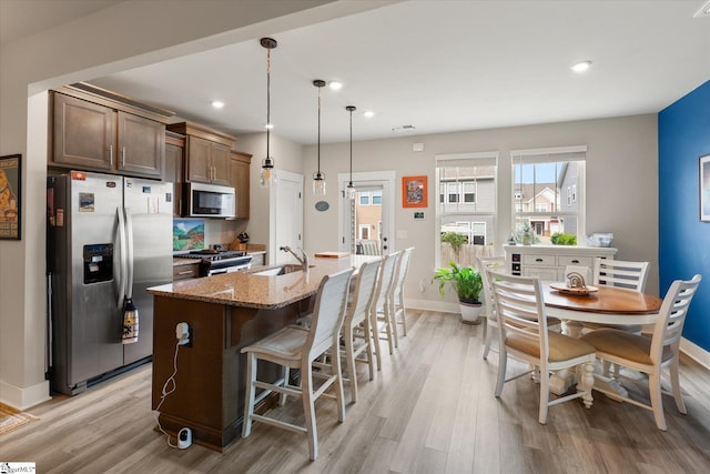 127 Addington Ln, Simpsonville, SC 29681 - kitchen featuring stainless steel appliances, an island with sink, light wood-style floors, light stone counters, and a kitchen breakfast bar
