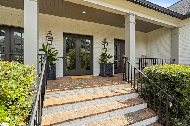 view of exterior entry featuring covered porch and french doors