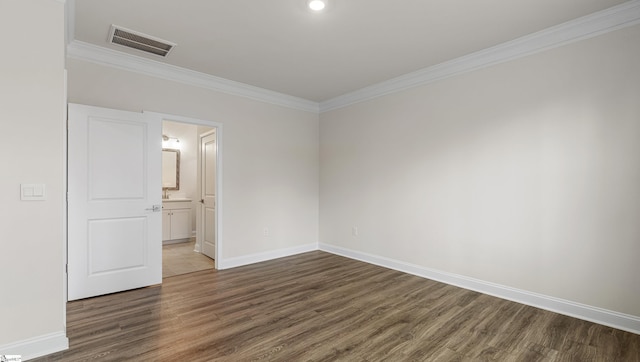 unfurnished bedroom featuring crown molding, ensuite bathroom, and dark hardwood / wood-style flooring