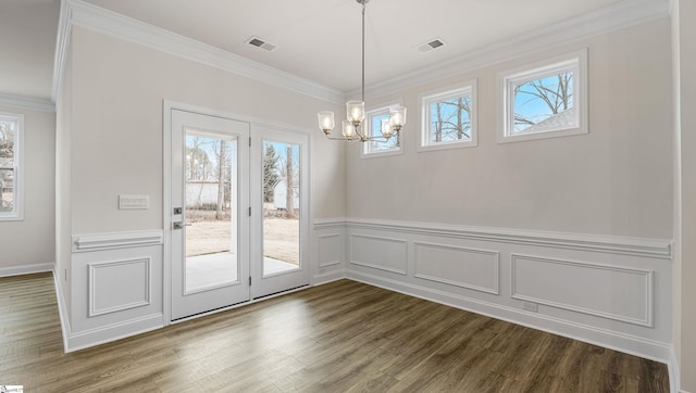 unfurnished dining area with a notable chandelier, crown molding, and dark wood-type flooring