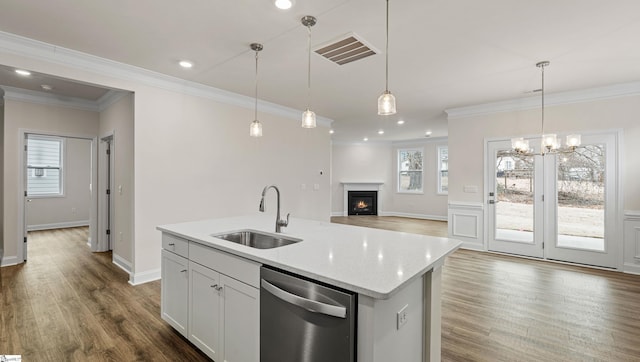 kitchen featuring sink, white cabinetry, hanging light fixtures, an island with sink, and stainless steel dishwasher