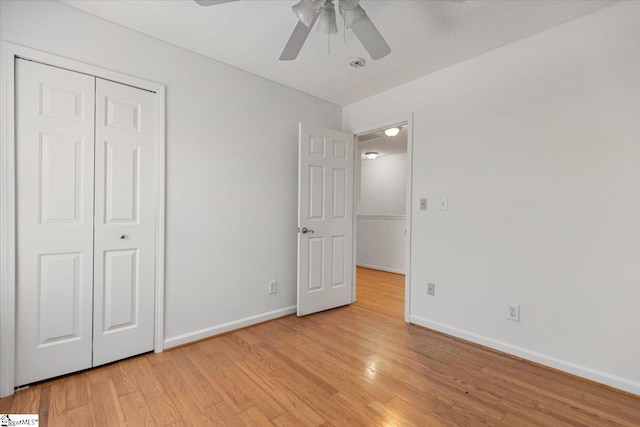 unfurnished bedroom featuring ceiling fan, a closet, a textured ceiling, and light hardwood / wood-style flooring